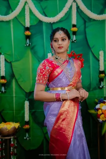 Bride in a lavender and red saree against banana leaves