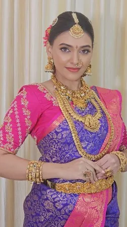 Bride in a pink and purple saree with layered temple jewellery