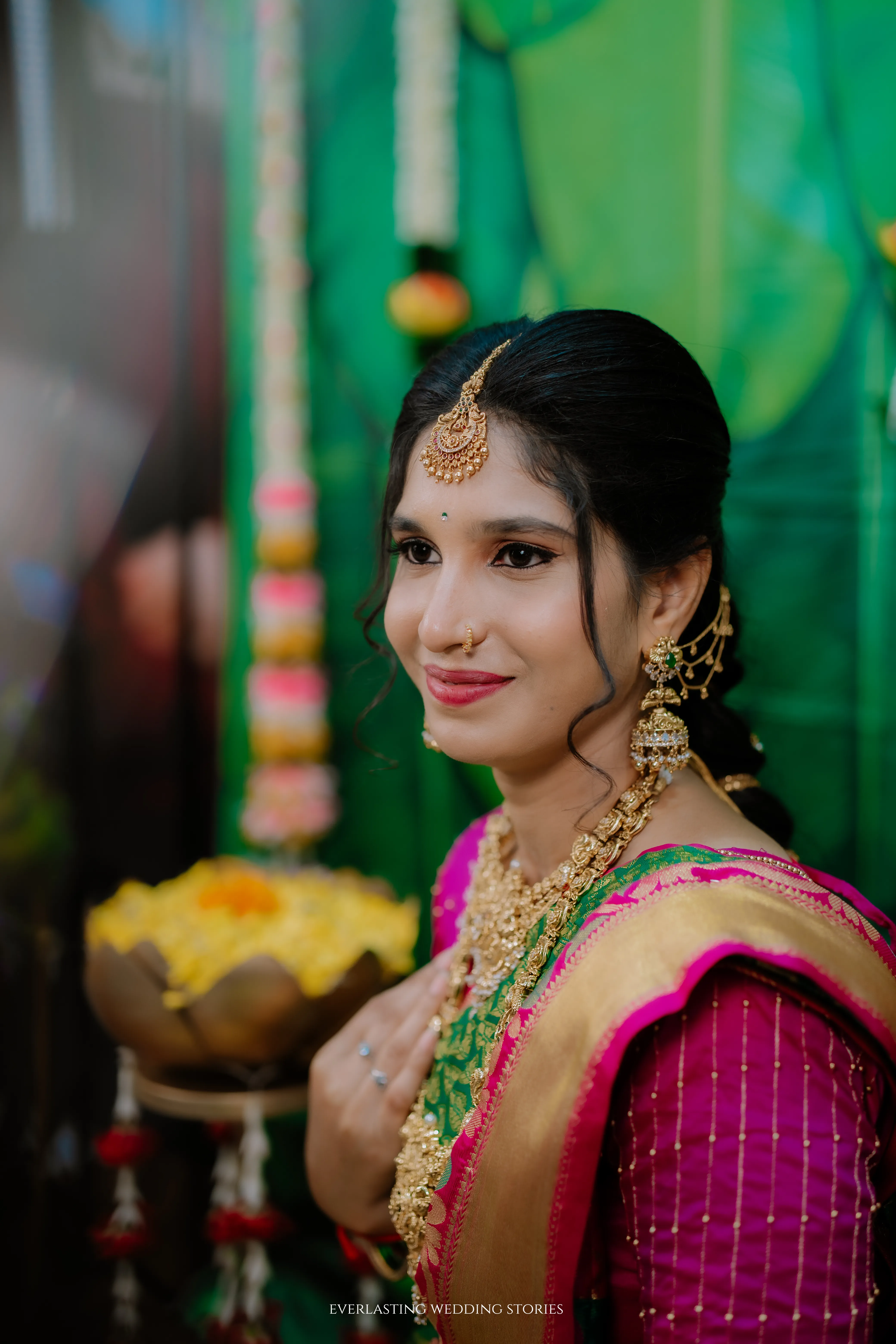 Bride in a pink saree with temple jewellery against green decor