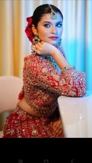 Bride in a red embroidered lehenga resting on a sofa