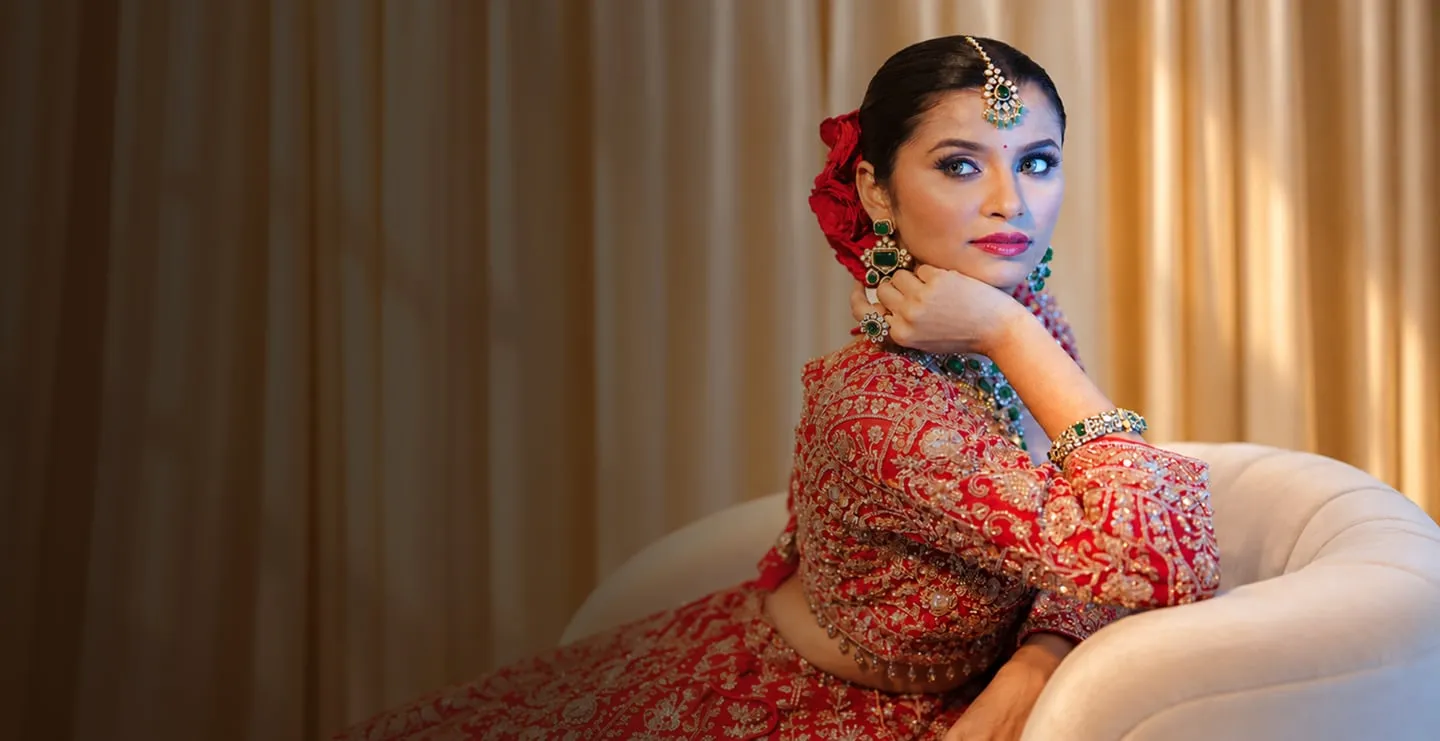 Bride in a red lehenga seated on an ivory sofa