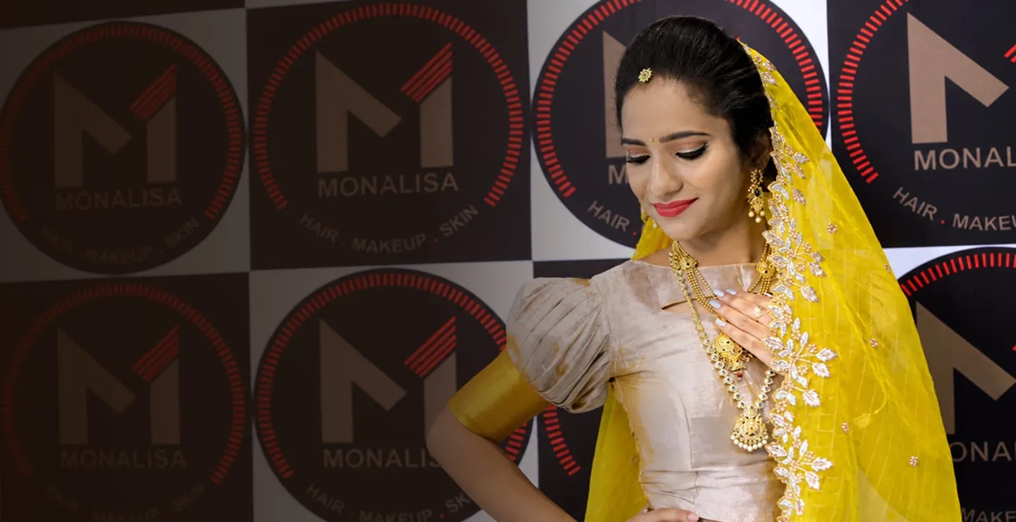 Bride in a yellow dupatta in front of the Monalisa logo wall