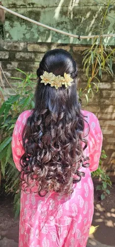 Long curls finished with a floral hair clip, seen from behind