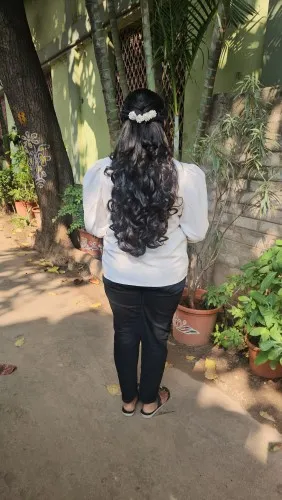 Half-up hairstyle with long curls and a pearl clip