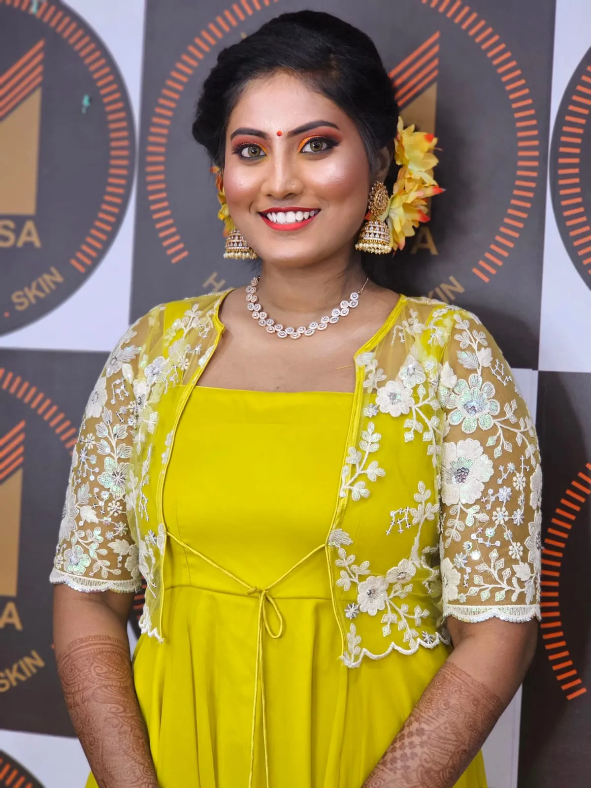 Model in a yellow outfit and lace jacket with floral hair accents
